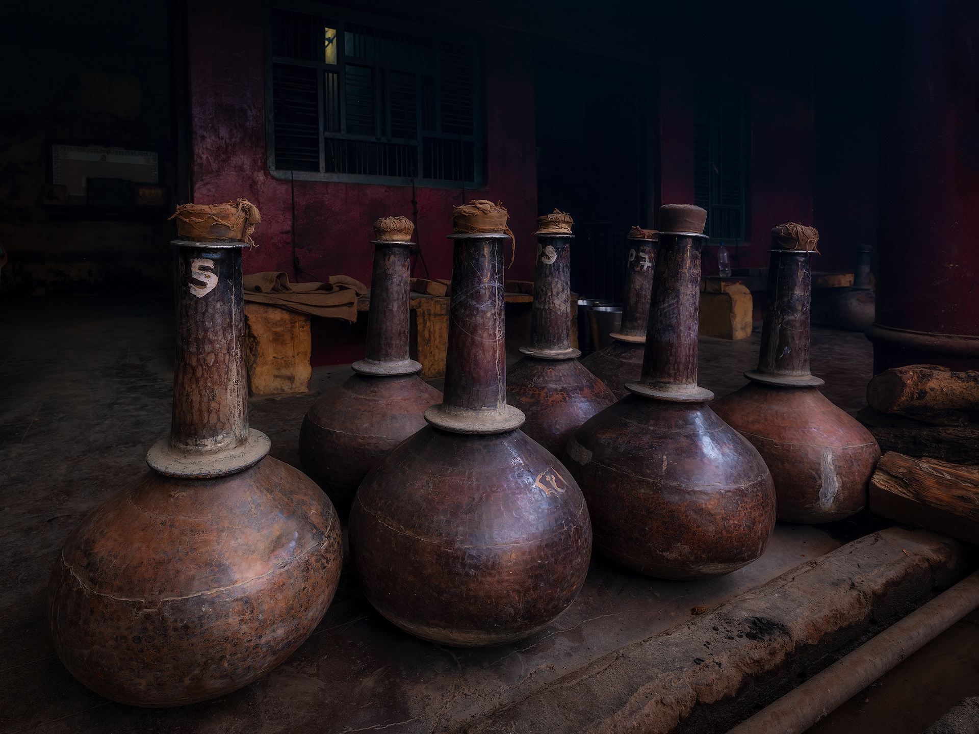 After the traditional distillation process is completed in Kannauj, the bhapka—the metal container where the fragrant vapors condense into liquid—is carefully detached from the deg and moved to a cool, shaded area. This step is essential to allow the natural separation of the essential oil from the hydrosol (water), which occurs as the liquid settles and cools. An experienced worker constantly monitors this phase for two main reasons: To ensure proper condensation and cooling, preventing the bhapka from overheating, which could affect the quality of the oil. To observe the separation process between the essential oil and water. Since the aromatic oil floats on top of the water, close supervision is necessary to avoid loss or contamination of the precious attar. Once the separation is complete, the essential oil is transferred into traditional leather bottles called kuppis, where it is left to mature and age over time. This aging process enhances the depth and complexity of the fragrance, giving Kannauj attar its unique and enduring character. Distillery Pranav.