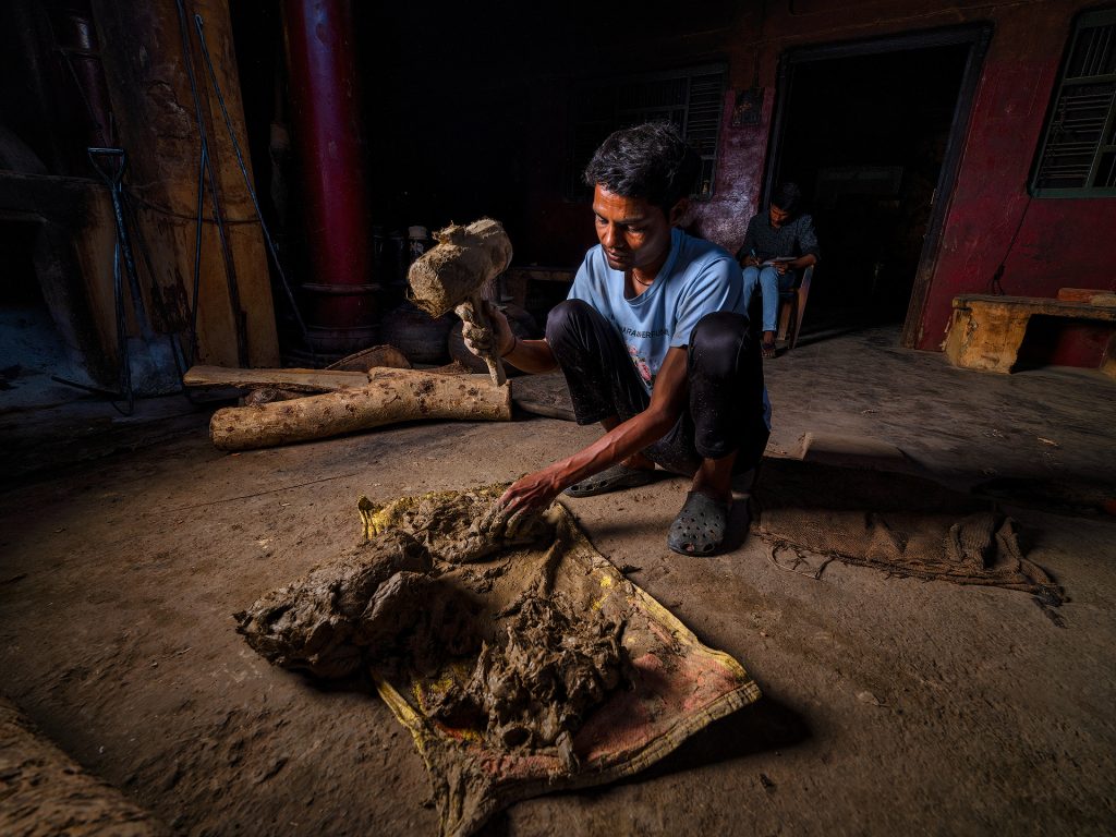 To seal the deg—the copper cauldron used in traditional distillation—a hand-prepared mixture of clay is applied just before the process begins.
The clay typically comes from local soil and has a key natural property: plasticity. This means it can be easily shaped and molded without breaking when mixed with water—similar to soft modeling clay or pottery material.
The mixture is then applied around the rim of the deg’s lid, along with wet cloth strips, to create an airtight seal. The goal is to prevent the fragrant steam from escaping during distillation, forcing it instead to travel completely through the chonga and into the bhapka, where it condenses.
Once the clay dries slightly and hardens with the heat, it forms a very effective natural seal.
At the end of the process, a hammer (hathoda) is used to break the now-dry clay crust and open the deg. Distillery Pranav.